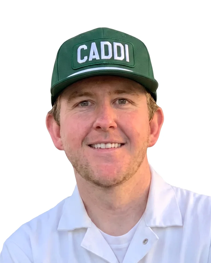 Caddi crew member in the white caddie uniform and green CADDI cap, arms crossed